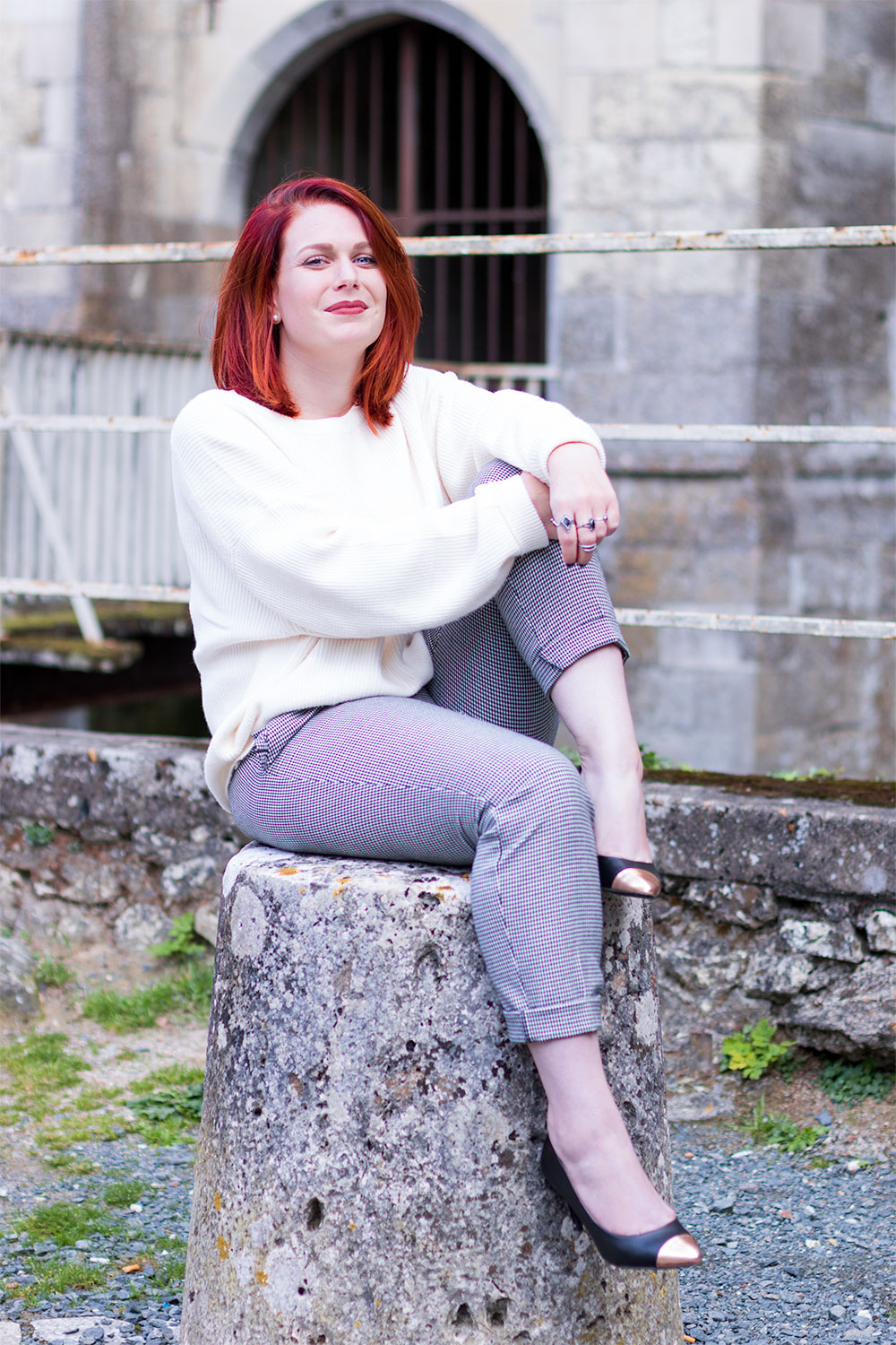 Assise sur la pierre devant le château d'amboise pour le look de la rentrée en pantalon pied-de-poule et pull blanc Zara