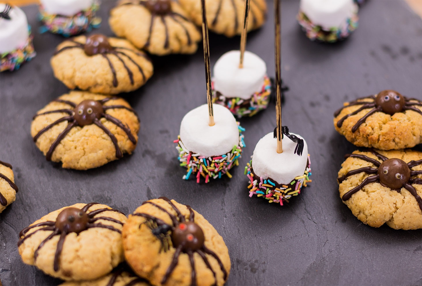 Zoom sur les chamallow enrobés de chocolat en forme de balais de sorcière et sur les cookies araignées pour le goûter d'Halloween