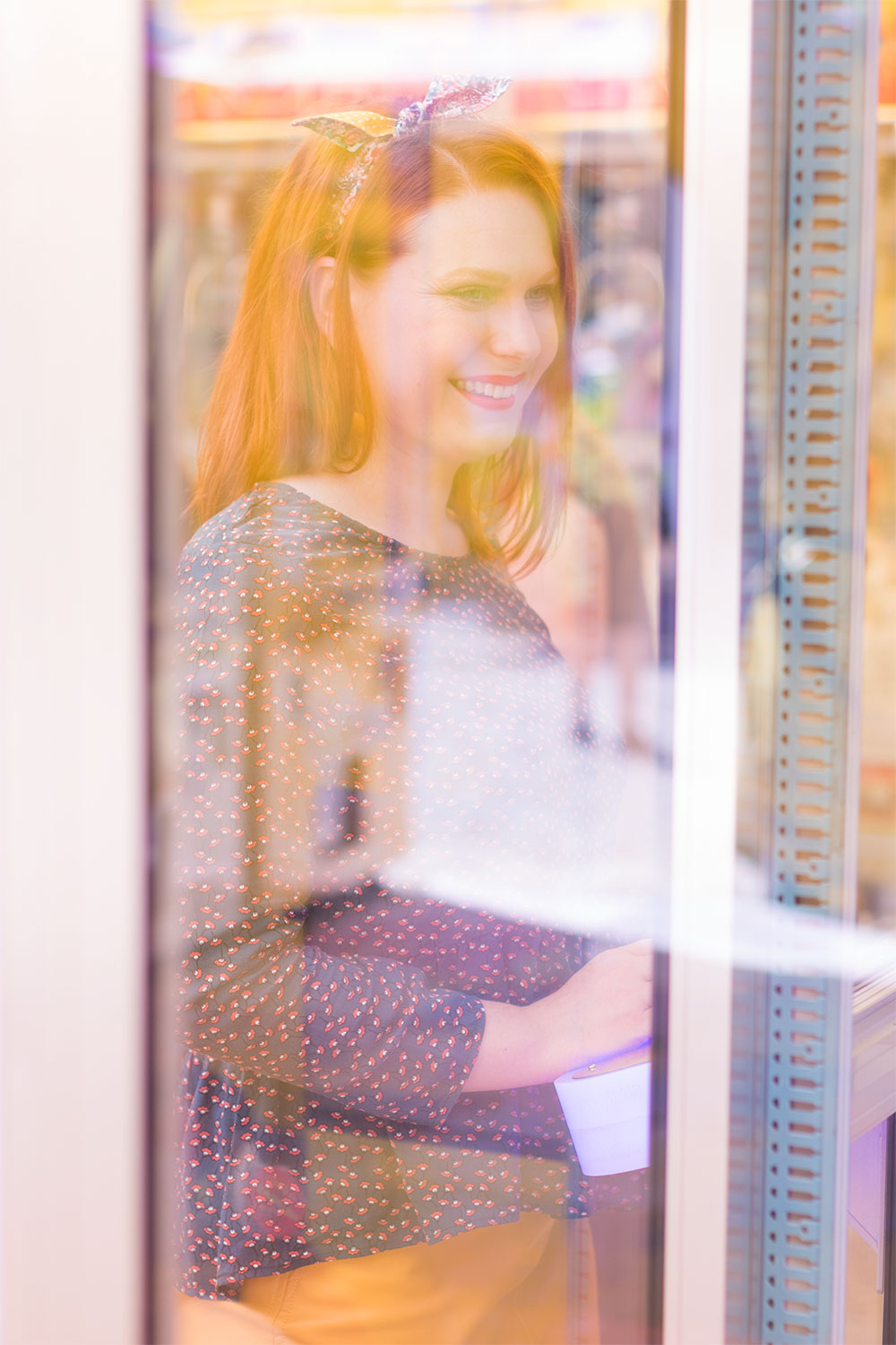 Sourire et look blouse et jupe derrière la vitre d'une machine à grappins de la fête foraine