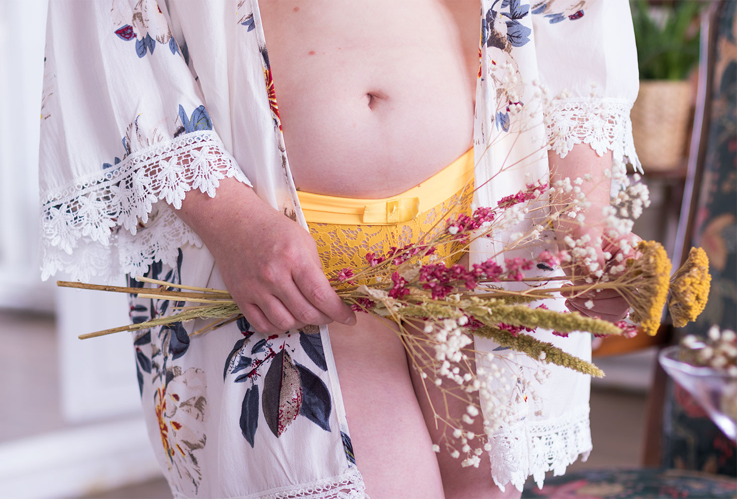 Culotte jaune en dentelle Pomm'Poire portée, vu de face, avec un kimono fleuri et un bouquet de fleurs séchées tenu juste devant