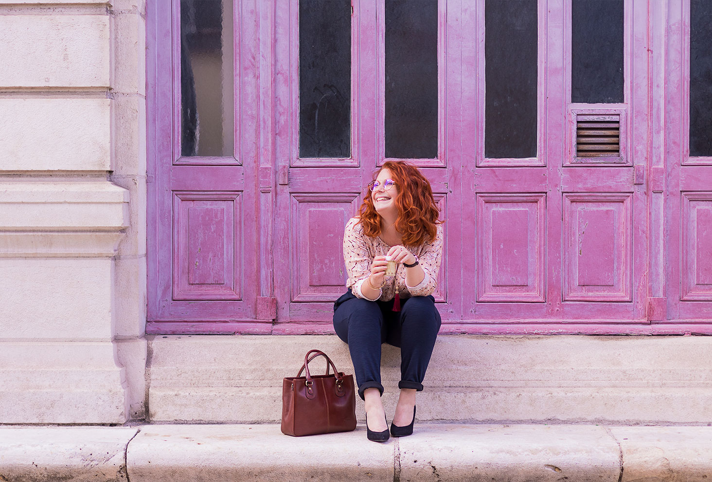 Assise sur les marches en pierre du grand théâtre de Tours, devant les portes vintages roses, en total look de working girl