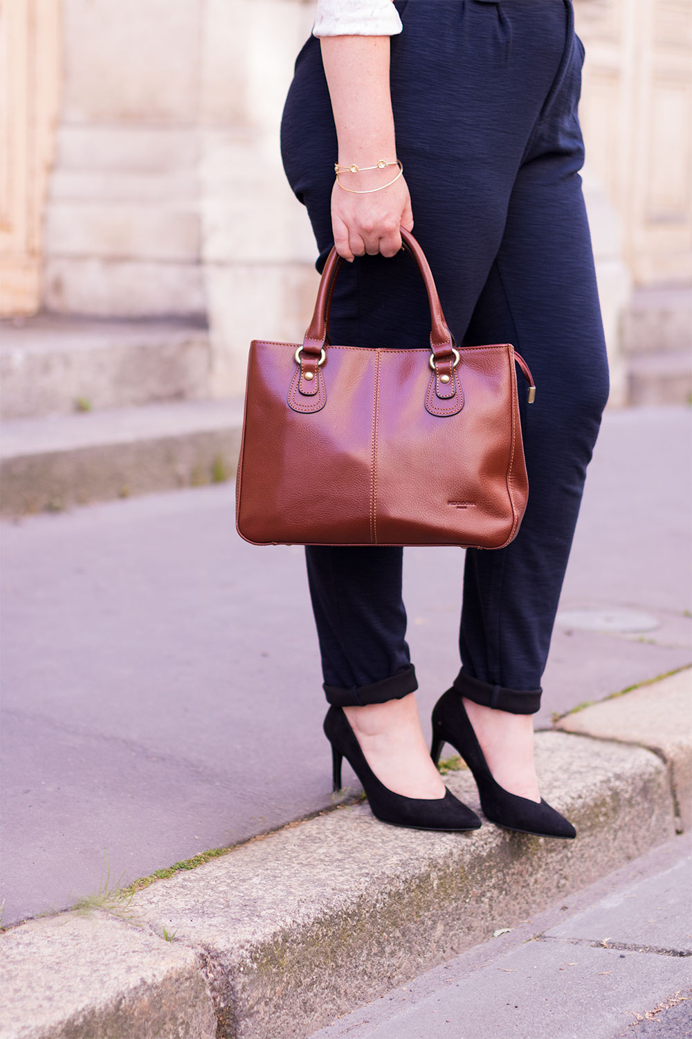 Le sac Hexagona Paris en action, porté avec un pantalon cigarette bleu marine et des escarpins noirs, prête à descendre le trottoir