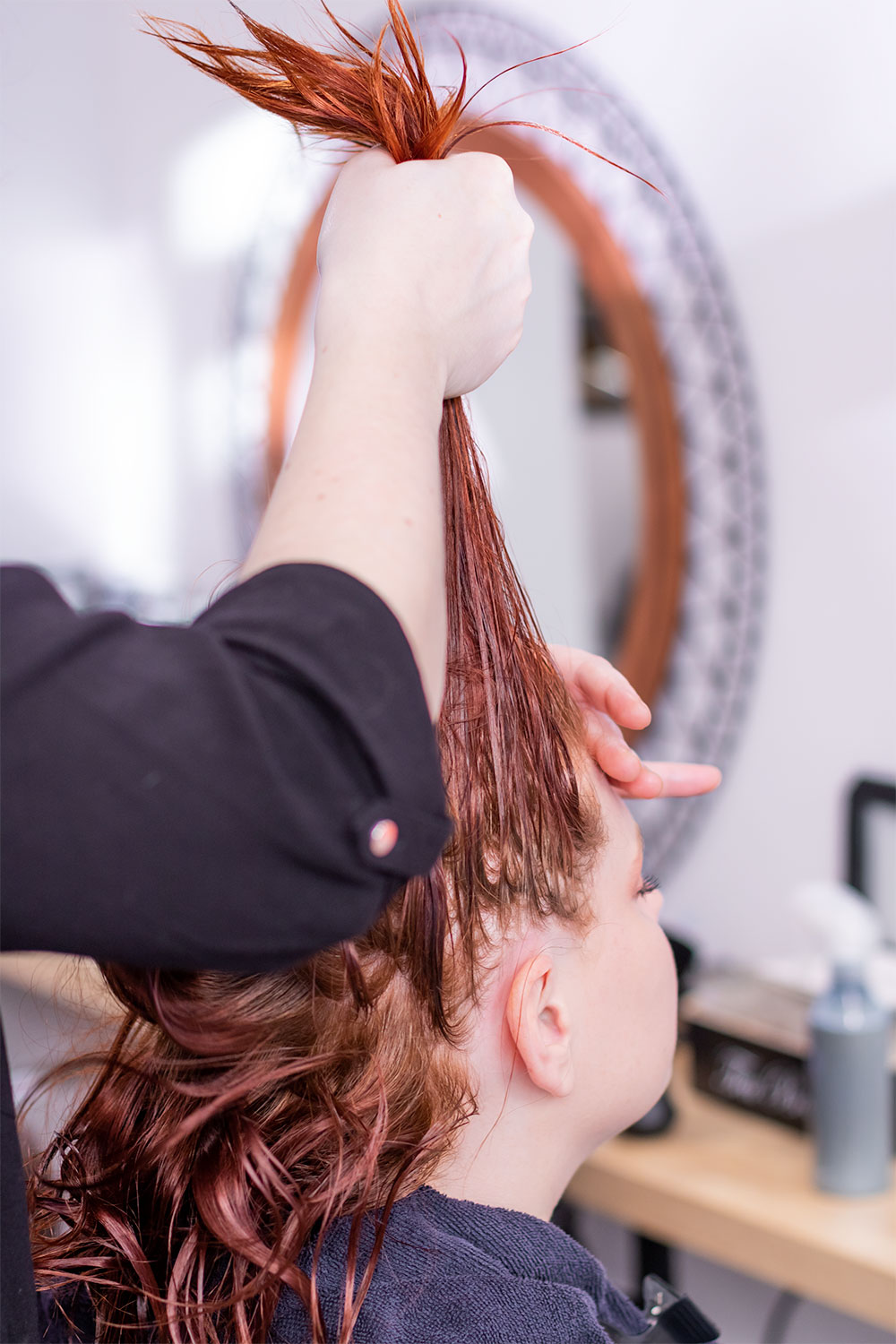 Massage du cuir chevelu aux huiles essentielles de dos les cheveux en l'air tenu par la coiffeuse du salon Artiste en Herbes à Tours