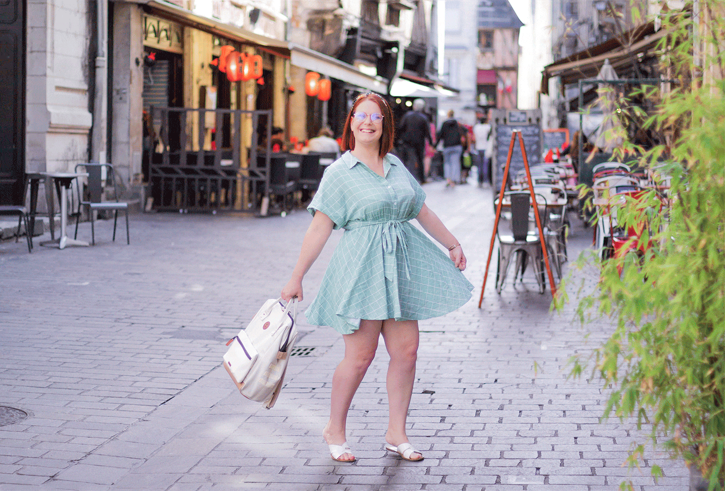 GIF animé d'un look de rentrée au milieu d'une rue, en robe verte qui tourne et sac à dos tenu dans la main