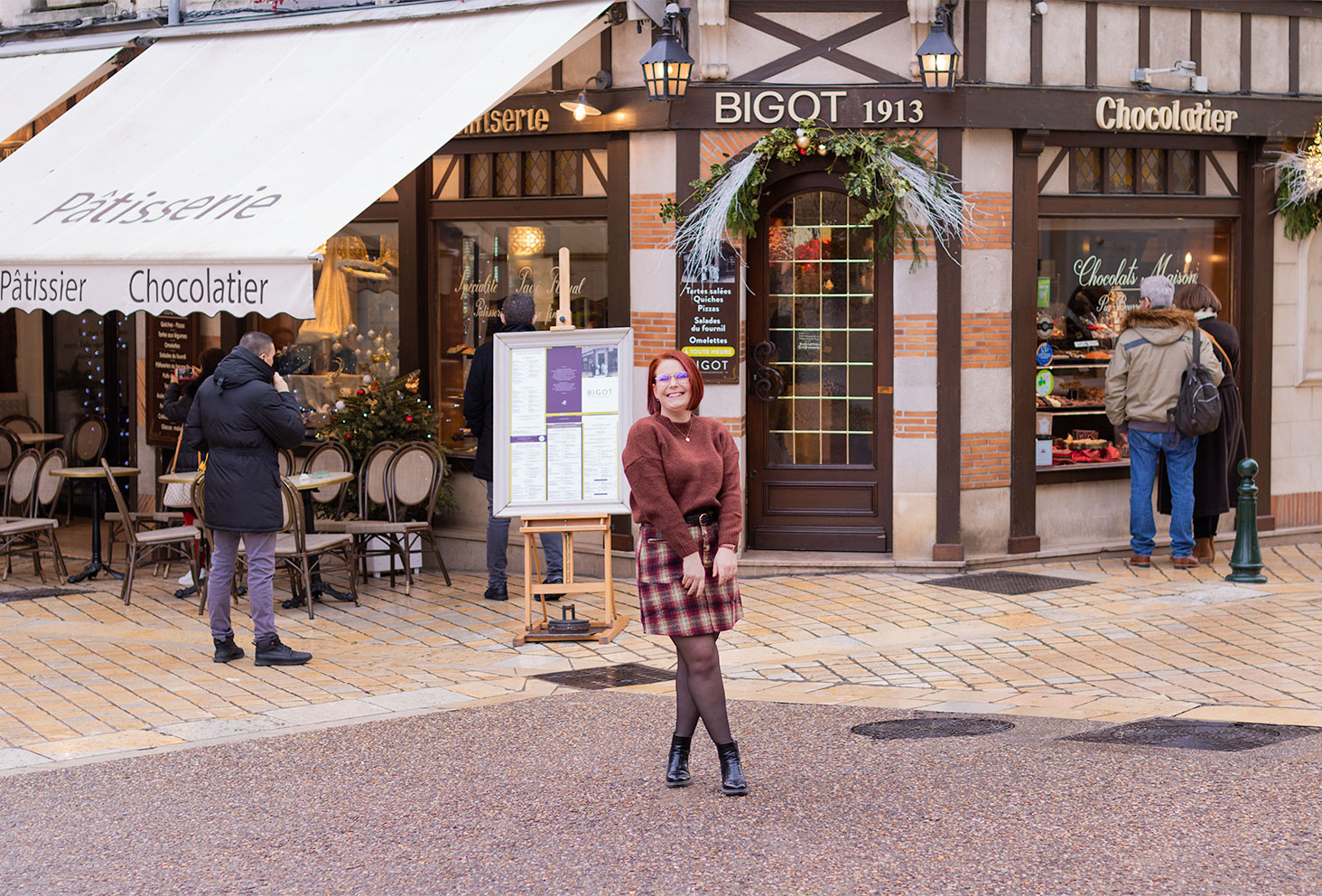 Devant la pâtisserie Bigot d'Amboise, en pull marron et jupe à carreaux, pour la résolution de 2020