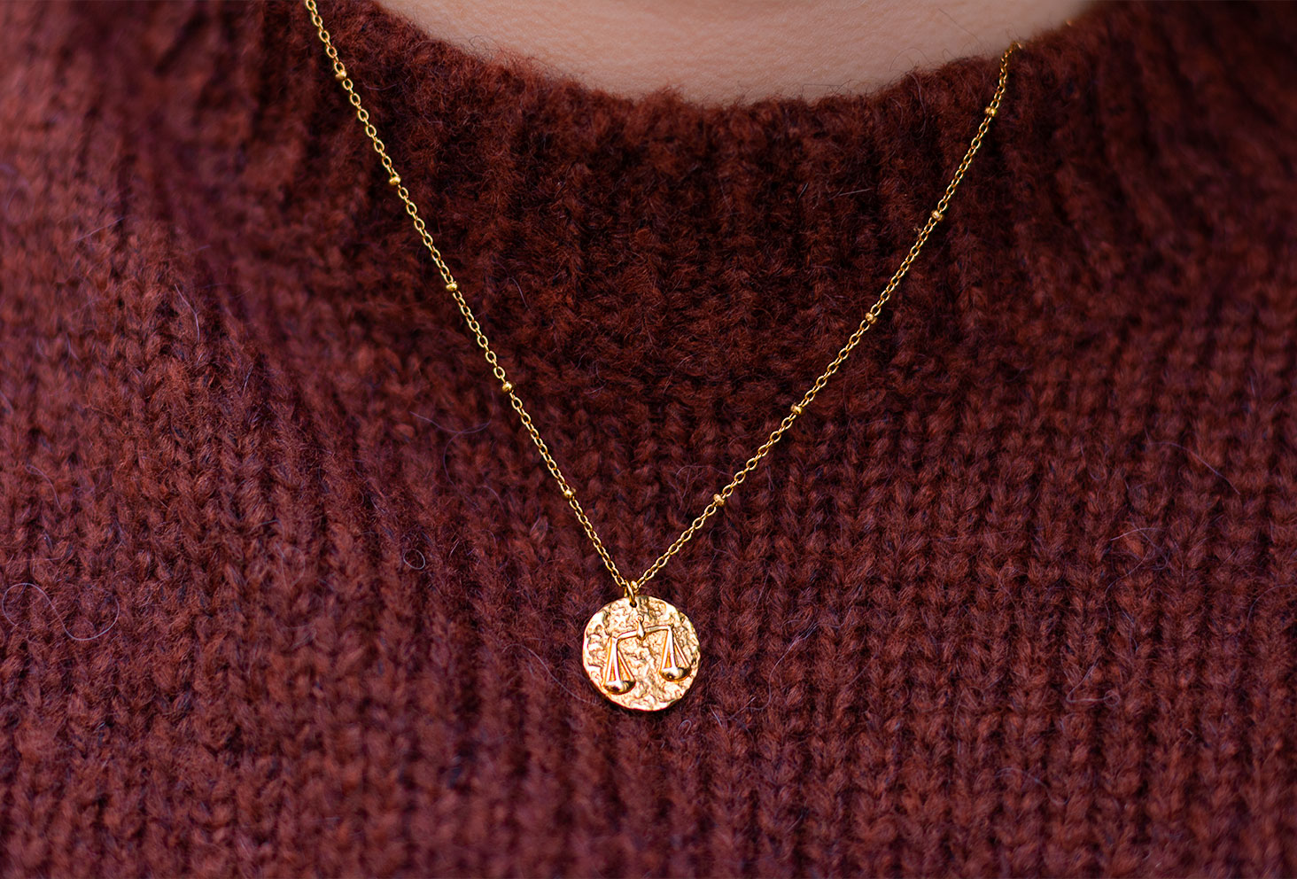 Zoom sur le médaillon du signe astrologique doré Balance en collier de la marque Adopt'