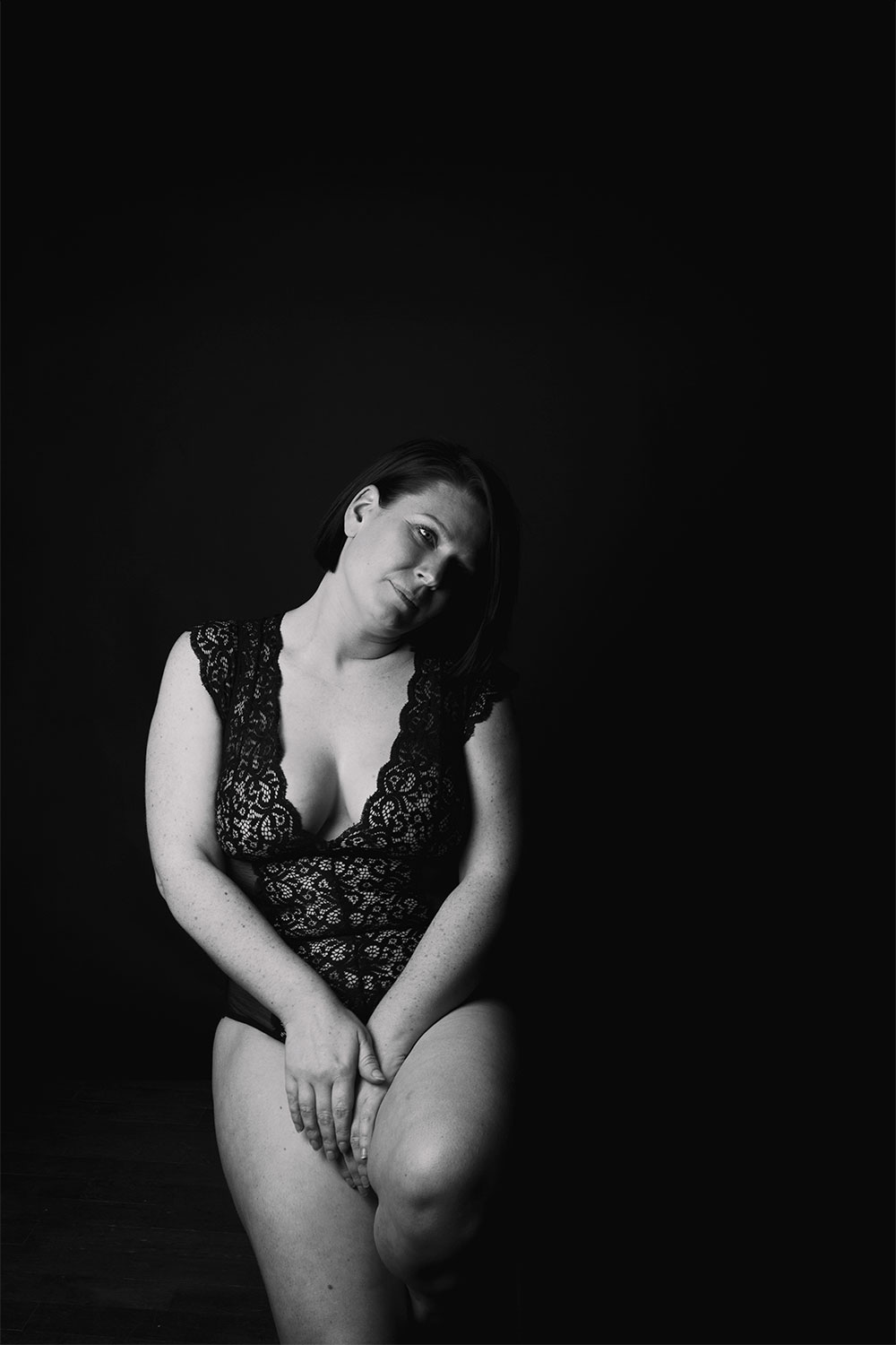 En studio shooting photo noir et blanc, dans un body en dentelle Pomm'Poire, pour parler body positive