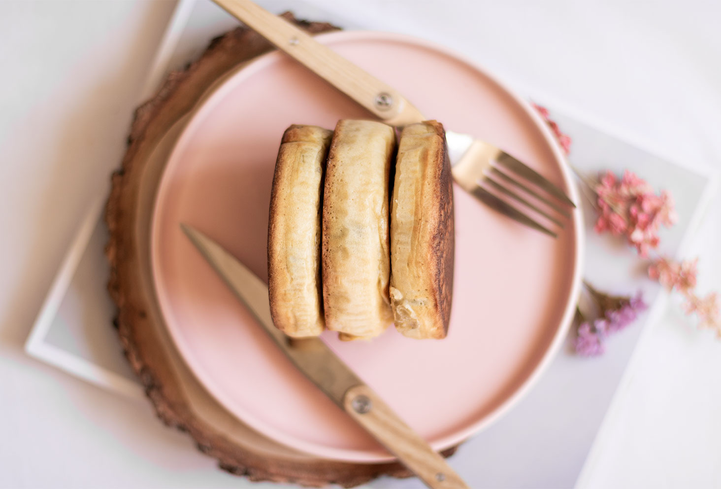 Zoom de côté des fluffy pancakes parfait pour un brunch, posés dans une assiette rose avec un couteau et une fourchette