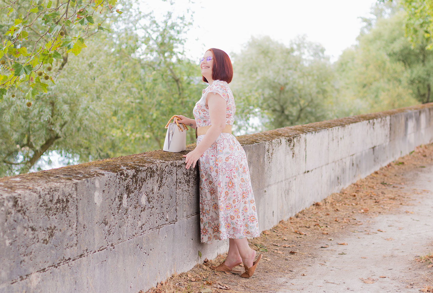 Sur la pointe des pieds pour regarder la Loire par-dessus un muret, avec le sourire, en robe longue à fleurs