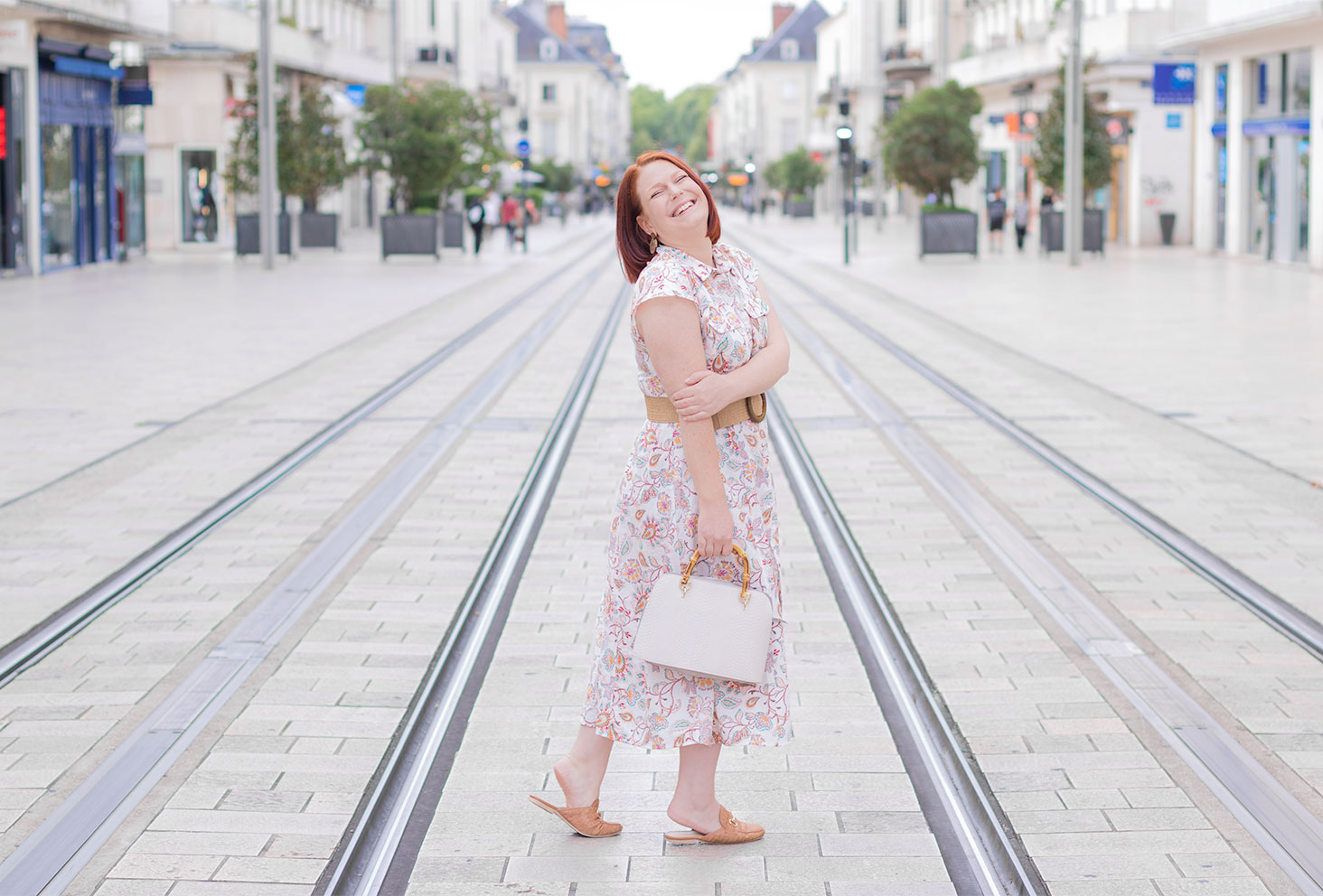 Au milieu de la rue Nationale de Tours, une main sur l'épaule avec le sourire, en robe chemise longue