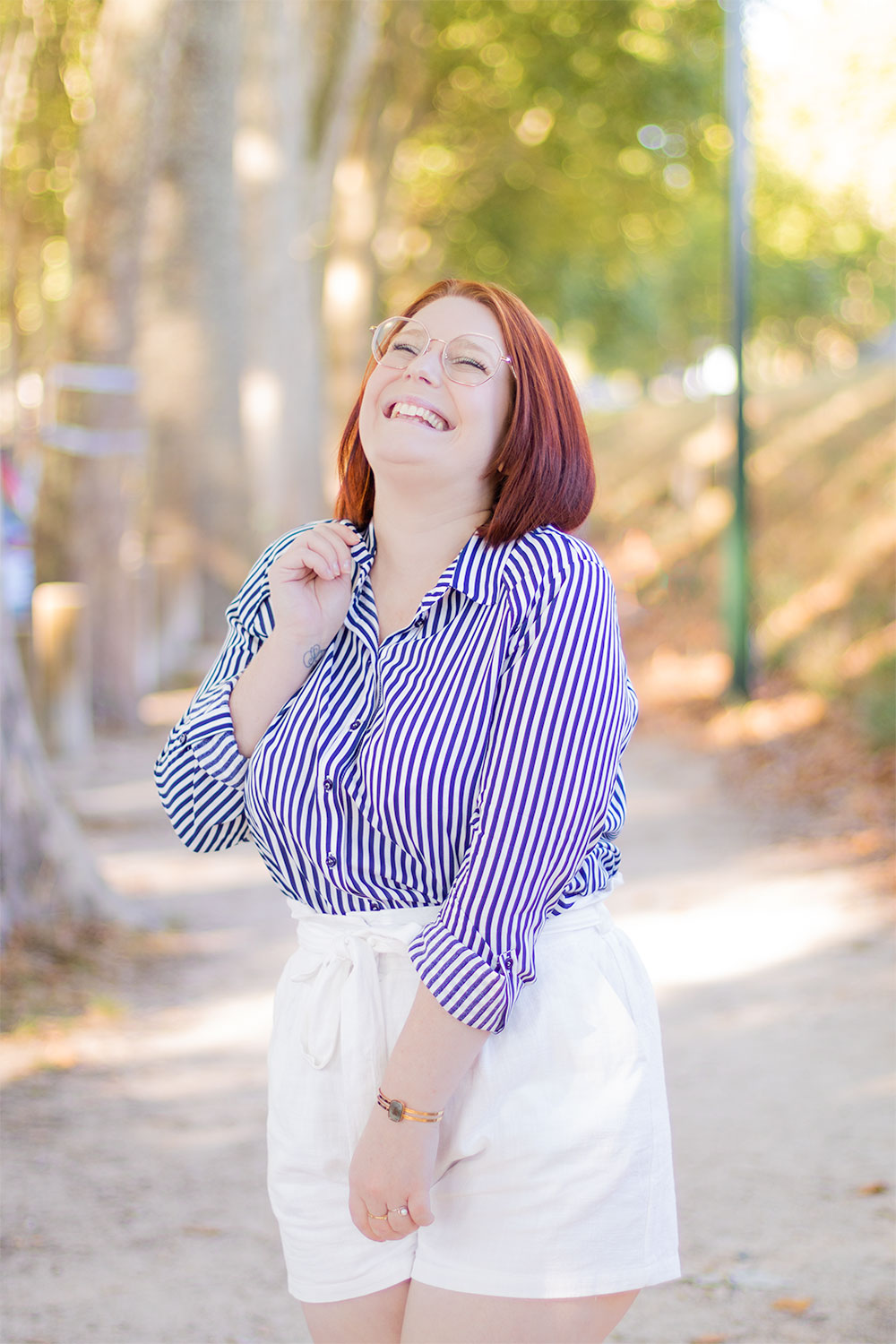 Chemise rayée et short blanc en lin, dans un décor boisé, avec le sourire