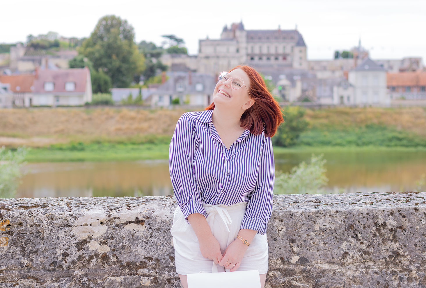 Le long des bords de Loire devant le château d'amboise, avec le sourire et les cheveux dans le vent, en chemise à rayures