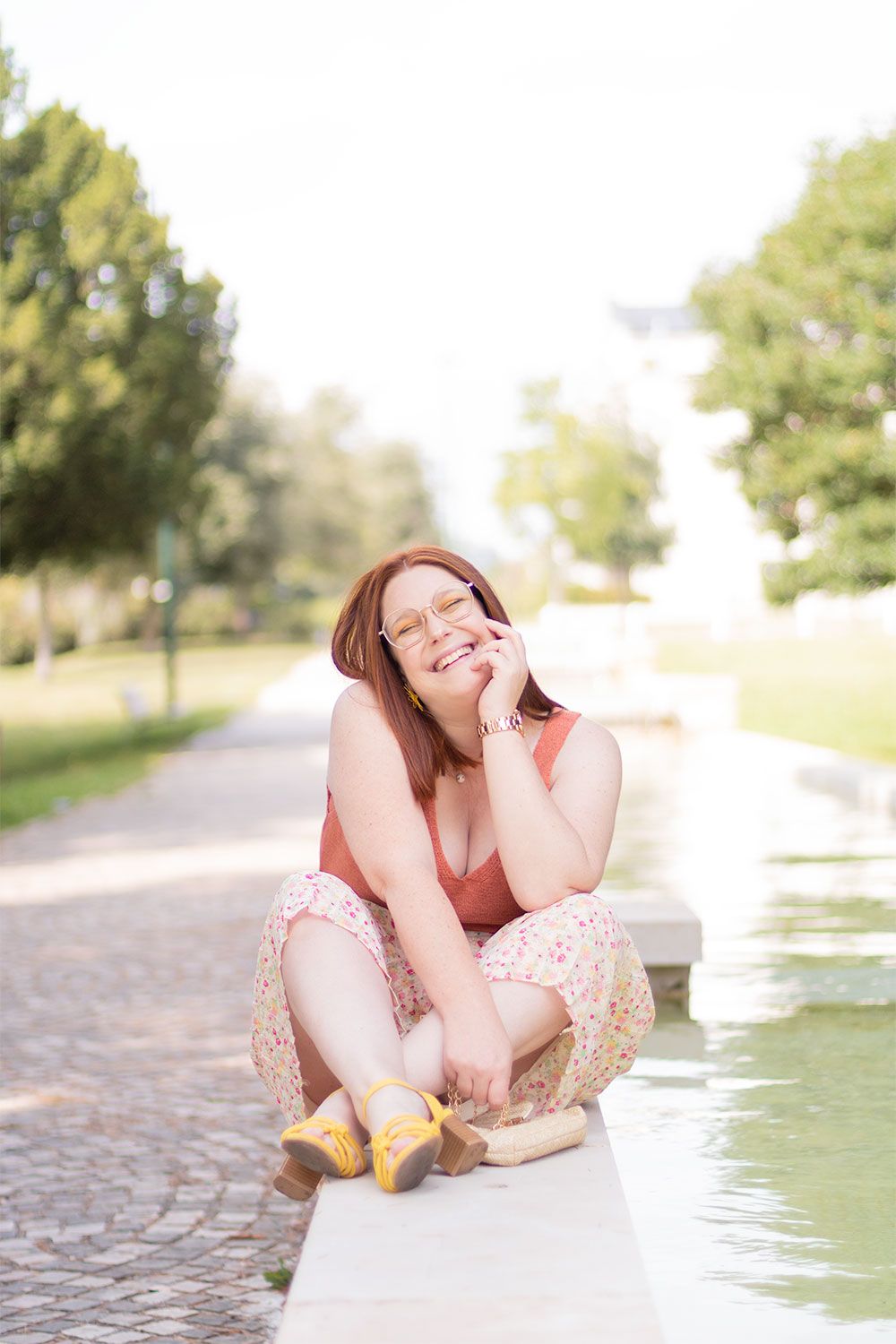 Assise sur le bord d'une fontaine en jupe à fleurs et sandales colorées