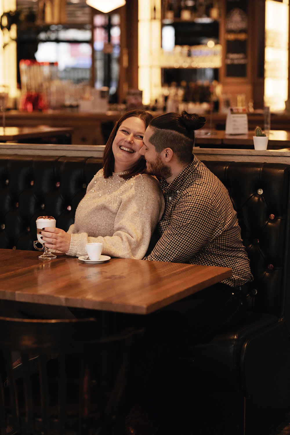Shooting couple assis sur une banquette en cuir dans un café avec un latté et un expresso