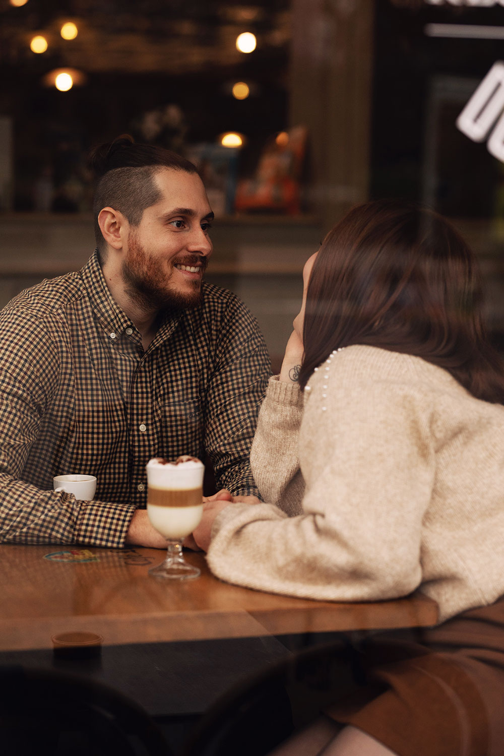 Couple amoureux assis à la table d'un café les yeux dans les yeux avec un cappuccino