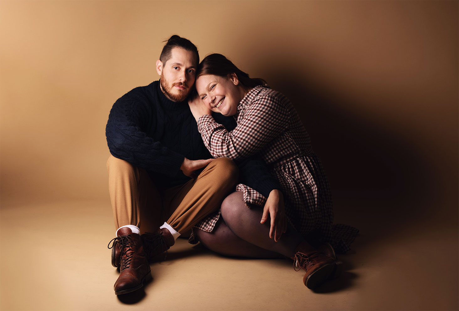 Couple assis au sol en studio photo devant un fond marron