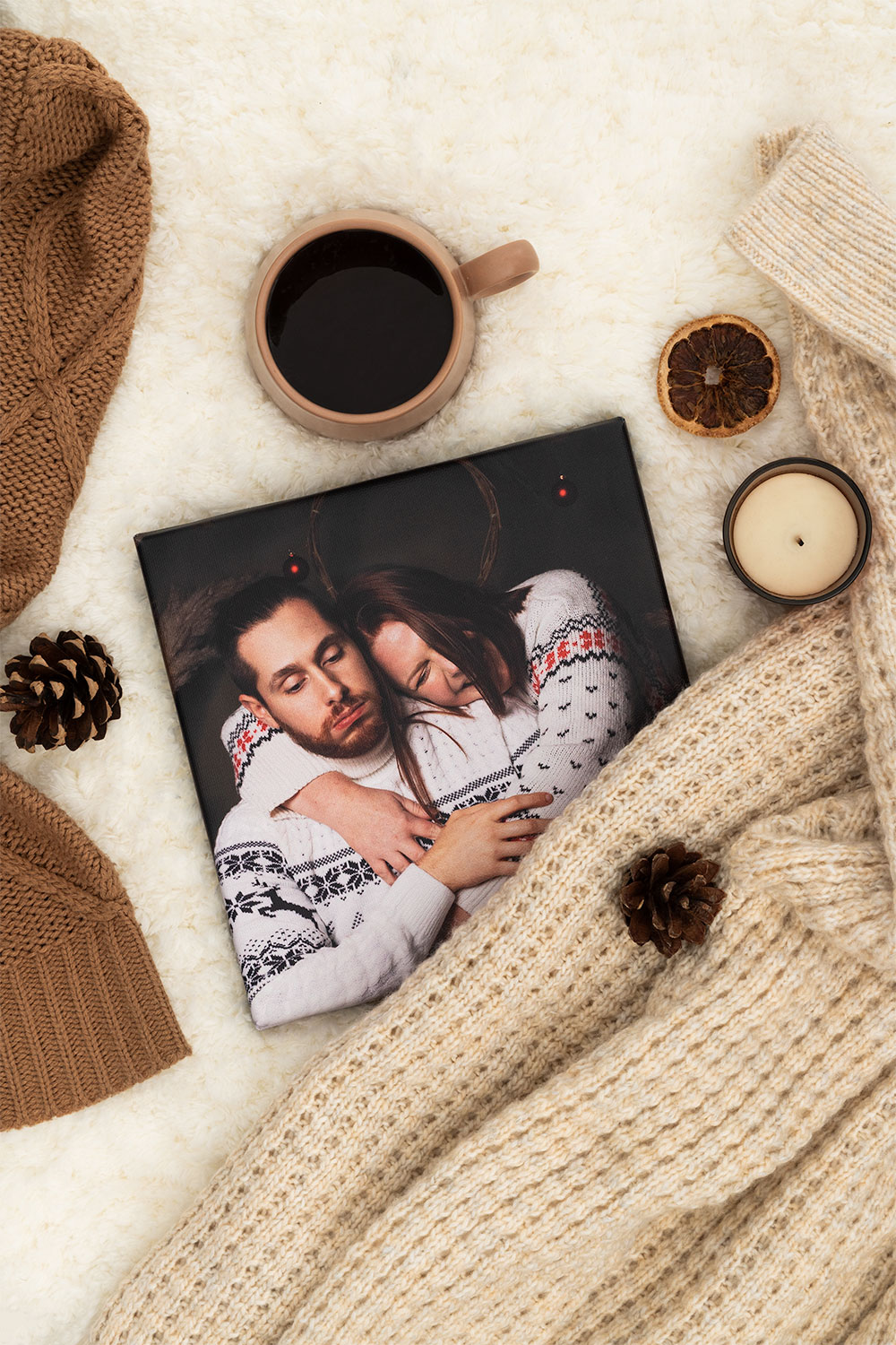 La photo sur toile pour un cadeau photo personnalisé posée sur un lit dans une ambiance cocooning avec un café et une bougie