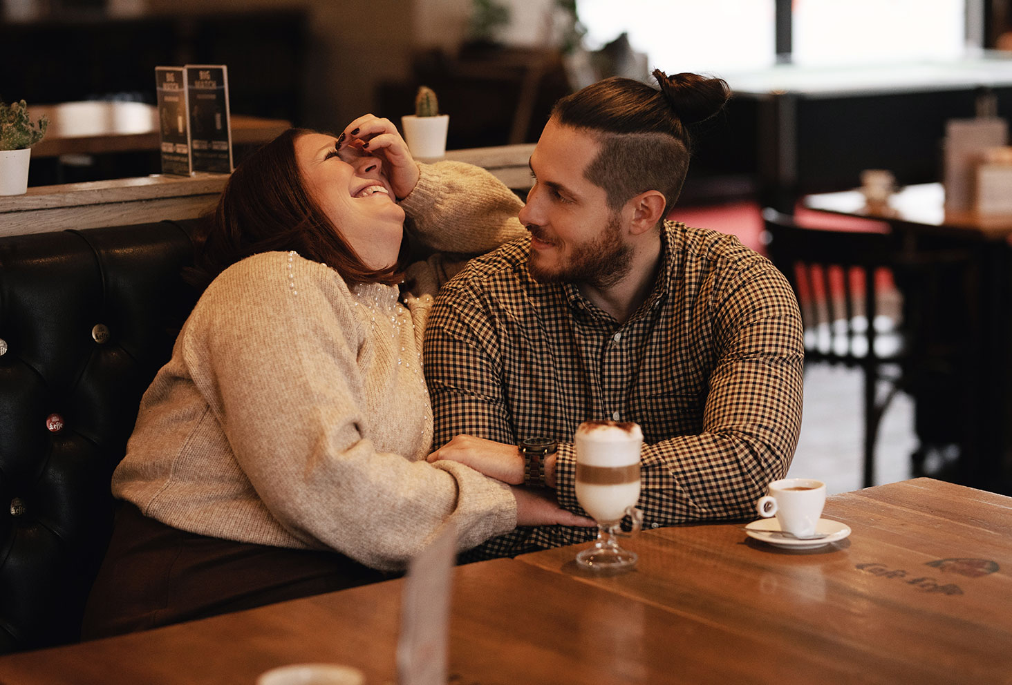 Couple en train de discuter dans un café avec un café et un cappuccino sur une table en bois