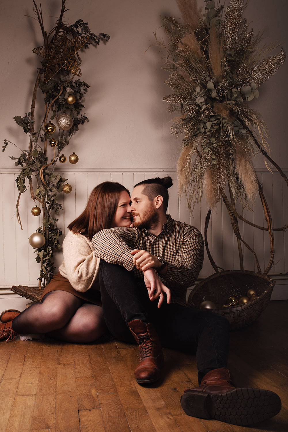 Shooting studio de Noël en couple dans un décor naturel et doré