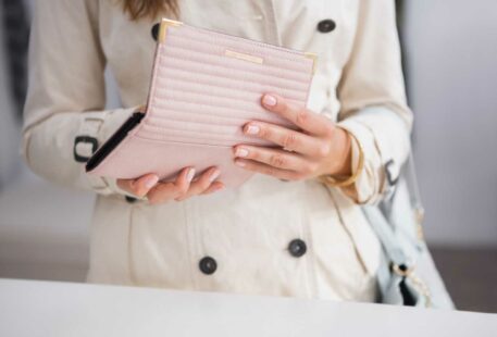 Portefeuille rose tenu entre les mains avec un trench beige